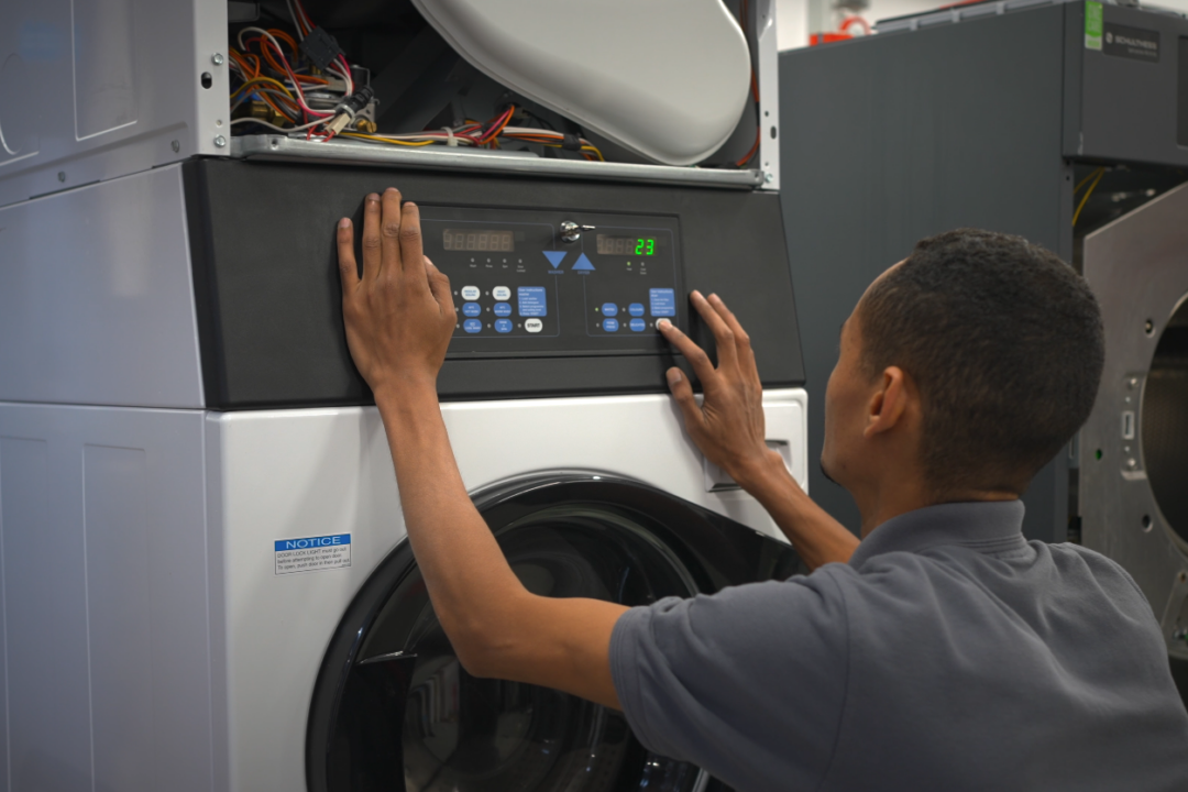 An engineer servicing a commercial laundry appliance.