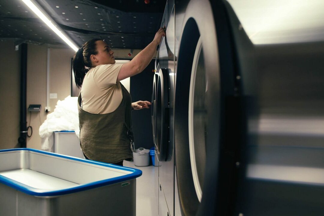 A worker loading a tumble dryer.