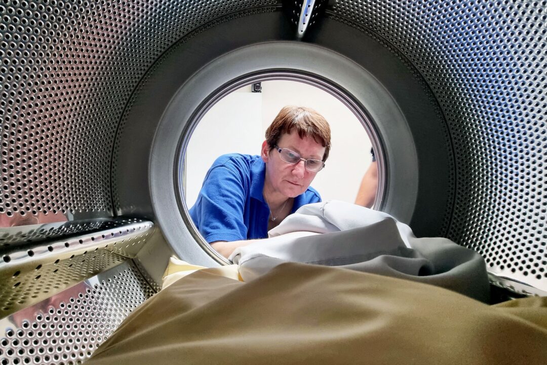The inside of a laundry machine drum, looking out at an employee